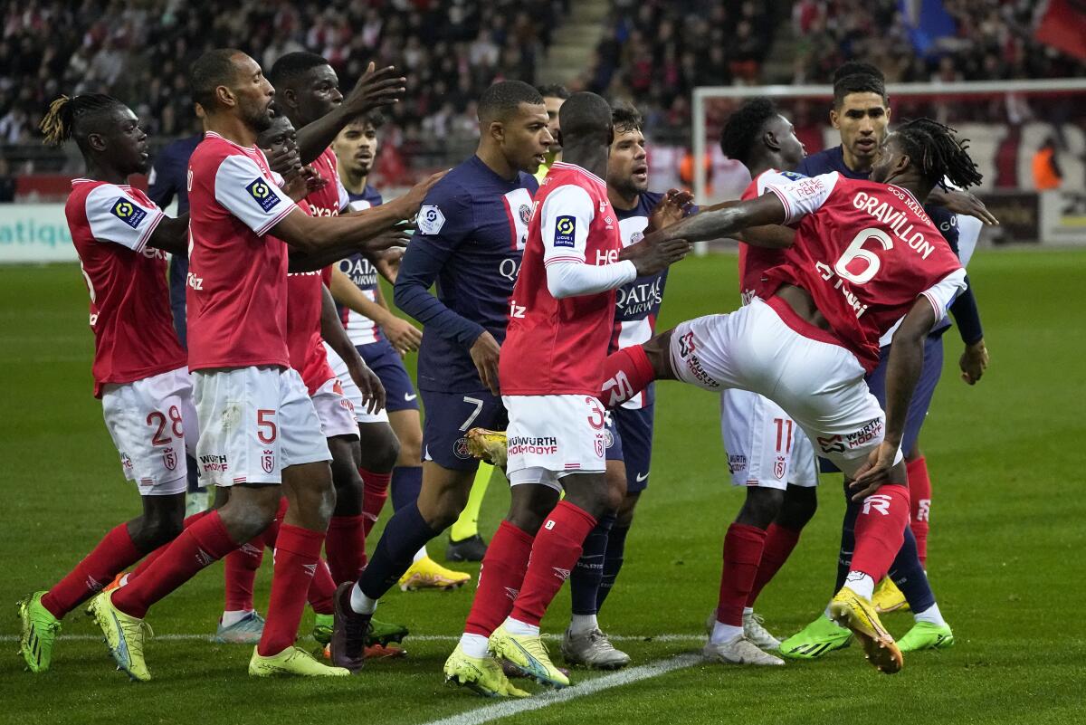 Reims' Andreaw Gravillon, right, clashes with PSG players during a French League One soccer match between Reims and Paris Saint-Germain, at the Stade Auguste-Delaune in Reims, eastern France, Saturday, Oct. 8, 2022. (AP Photo/Michel Euler)