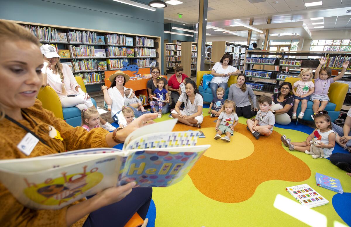 Annika Helmuth, the branch librarian at the Corona del Mar library, reads a book during Books & Babies Storytime on Tuesday