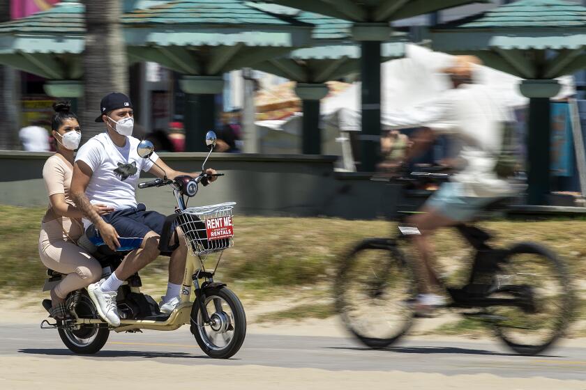 VENICE, CA - AUGUST 09, 2020: People wear protective masks against the coronavirus while making their way along the bicycle path in Venice Beach. (Mel Melcon / Los Angeles Times)