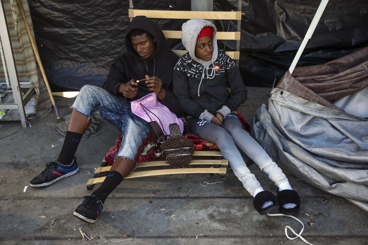 J.T. Jackson and his girlfriend Lae Cockrell sit on a chair on the sidewalk