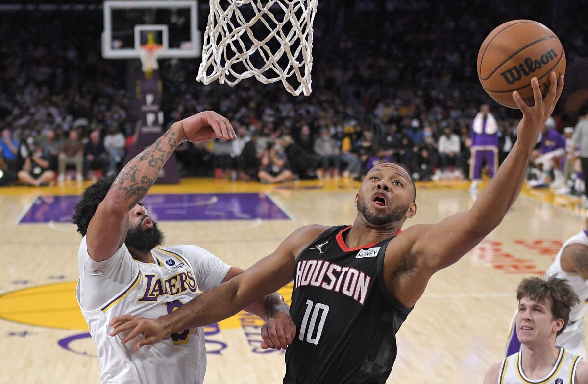 Eric Gordon attempts a left-handed layup while Lakers forward Anthony Davis attempts to block the shot.