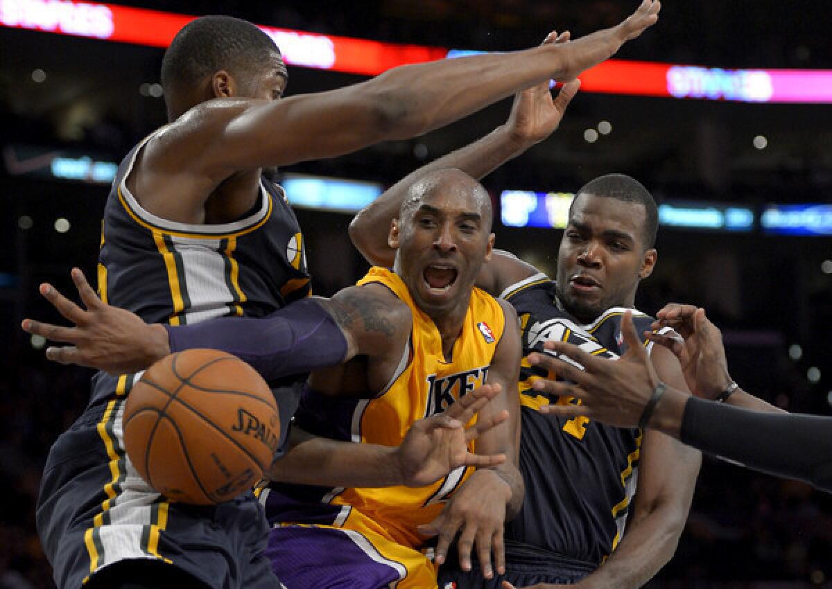 Kobe Bryant makes a pass after driving down the lane against Jazz big men Derrick Favors and Paul Millsap during a game at Staples Center.
