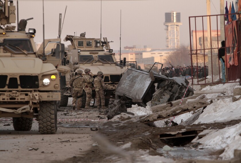 U.S. soldiers and Afghan security forces search the site of a suicide bombing in Kabul.
