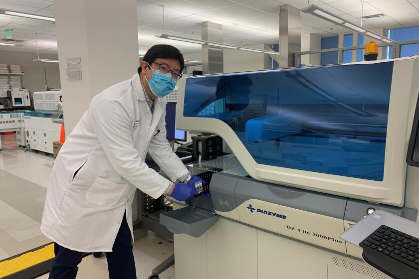 Dr. Ray Suhandynata loads samples for analysis on the Diazyme DZ-Lite 3000Plus analyzer at UCSD CALM. This instrument measures concentrations of antibodies directed against the virus that causes COVID-19.