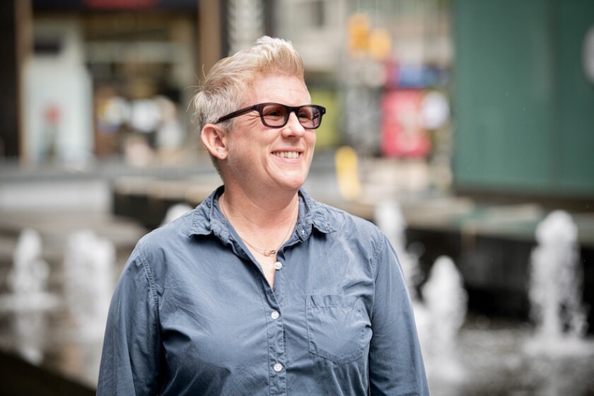 A woman smiling in a blue shirt and glasses.