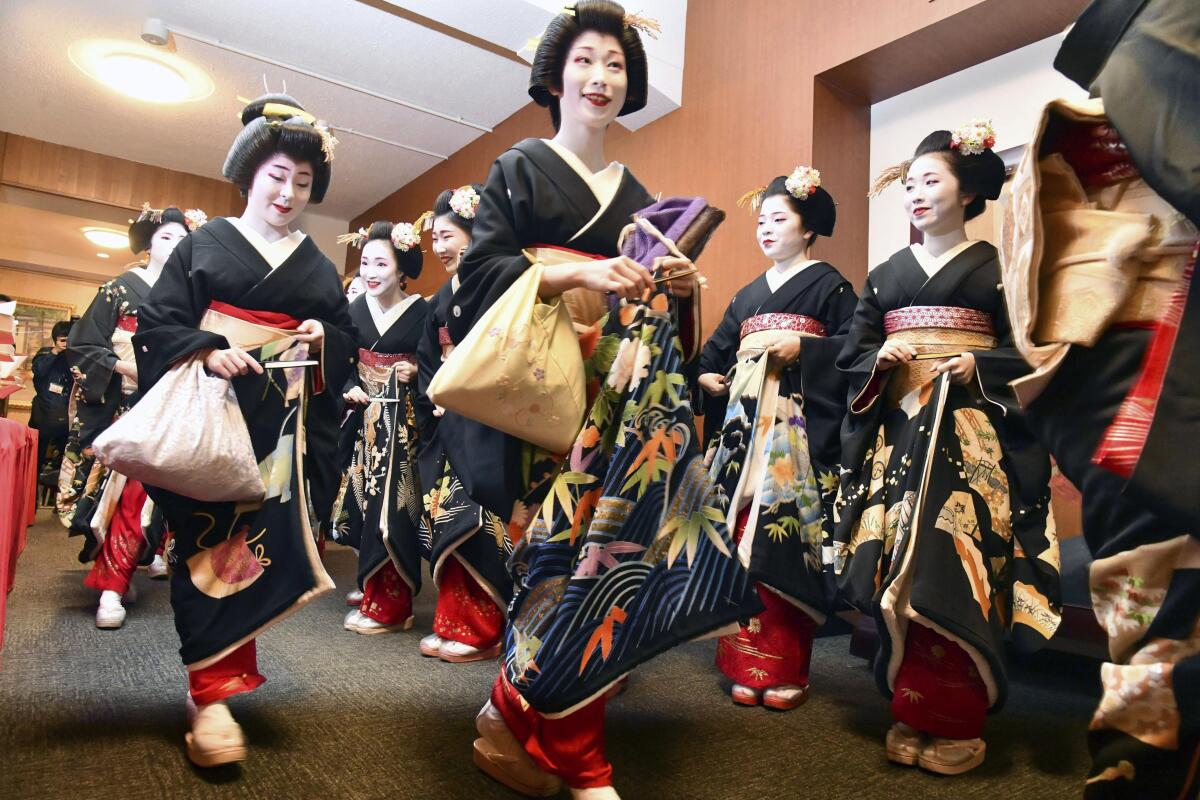 Kimono-clad geiko and maiko professional entertainers arrive for a ceremony.