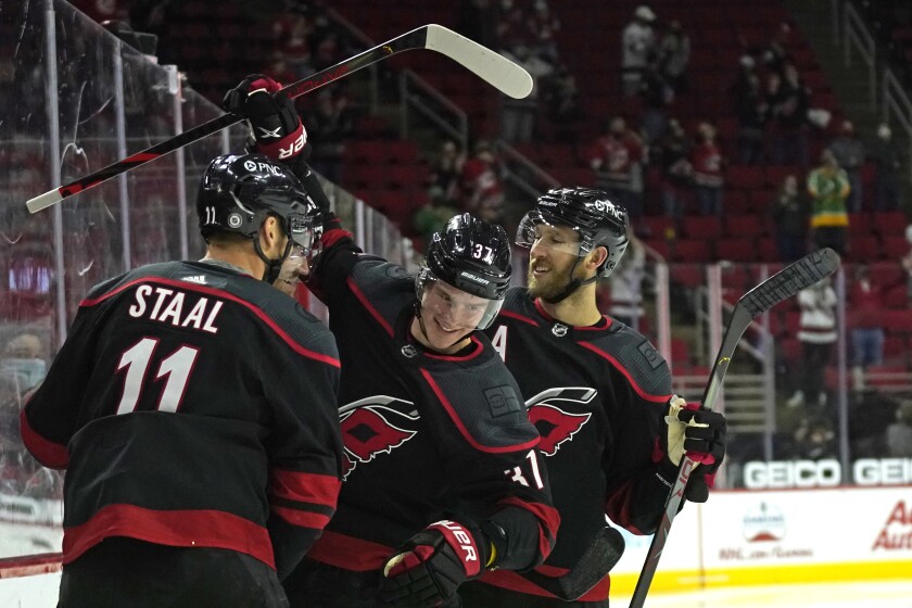 Carolina Hurricanes center Jordan Staal (11) and defenseman Jaccob Slavin, right, congratulate right wing Andrei Svechnikov (37) following Svechnikov's goal against the Nashville Predators during the second period of an NHL hockey game in Raleigh, N.C., Thursday, April 15, 2021. (AP Photo/Gerry Broome)