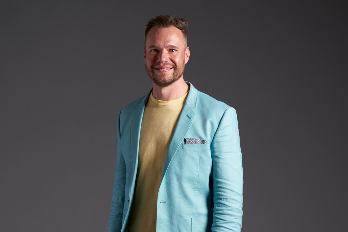 Nick Thompson of 'Love Is Blind' smiles as he poses in a light blue blazer and yellow shirt