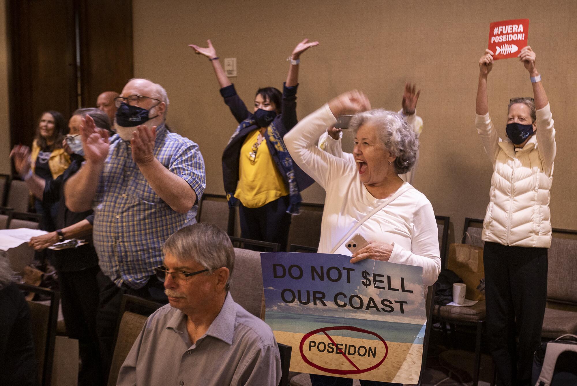 Debbie Andrews, center, of Huntington Beach, celebrates with others as the California Coastal Commission rejects a plan