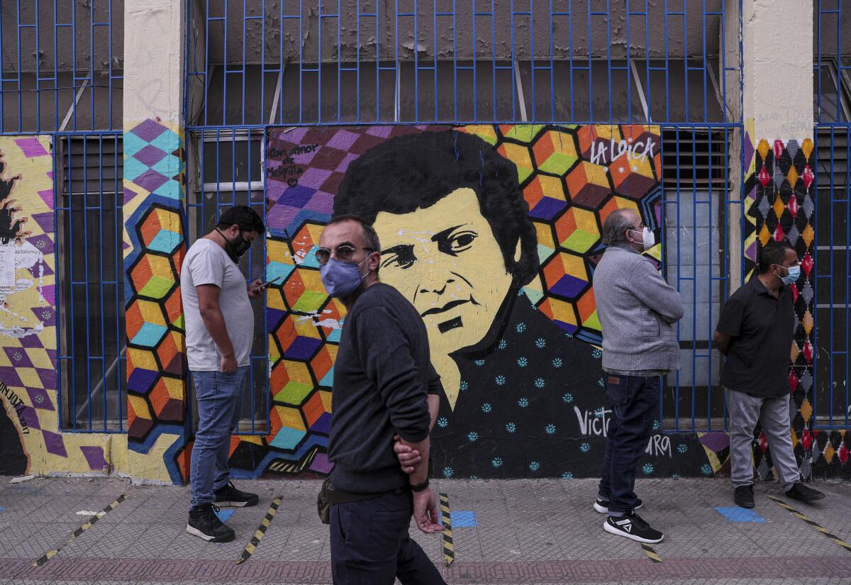 ARCHIVO - Los votantes se alinean frente a un mural que representa al fallecido cantautor folklórico Víctor Jara