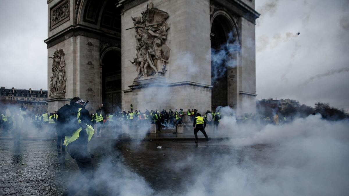 Demonstrators clash with riot police at the Arc de Triomphe in Paris last week during a protest against rising oil prices and living costs.