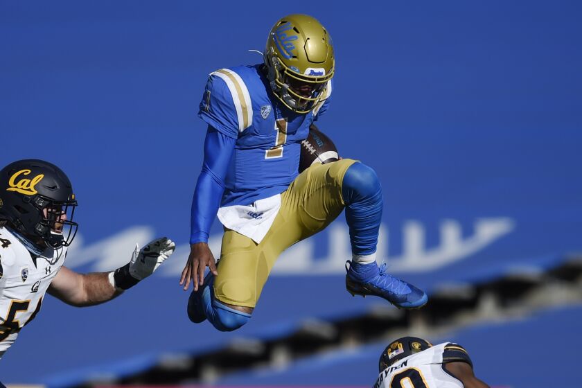 UCLA quarterback Dorian Thompson-Robinson, center, leaps over California cornerback Josh Drayden.