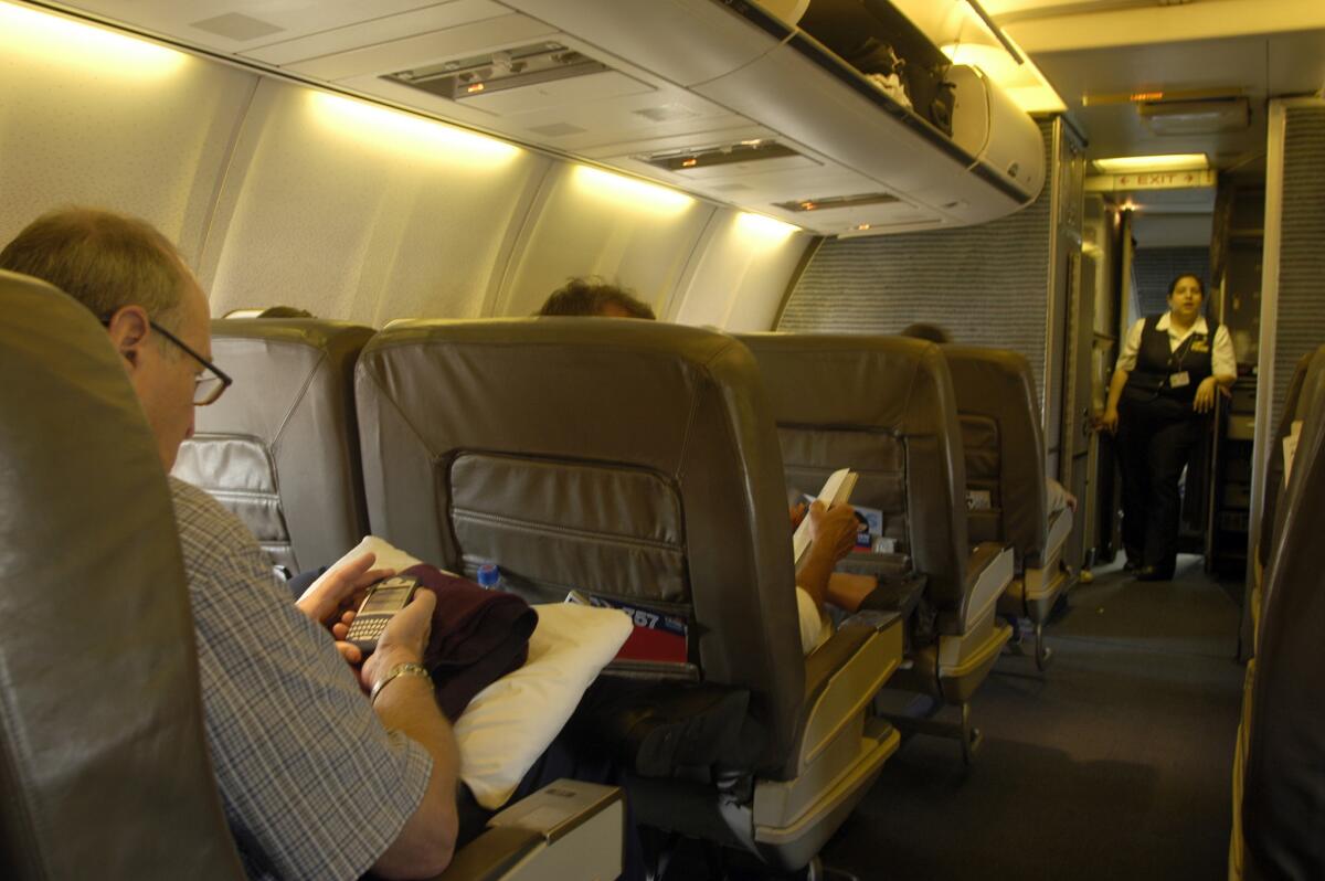 An American Airlines passenger in first class makes a last-minute check of his Blackberry before takeoff at Miami International Airport. The airline will only serve meals to first- and business class passengers on flights longer than two hours and 45 minutes, starting Sept. 1.