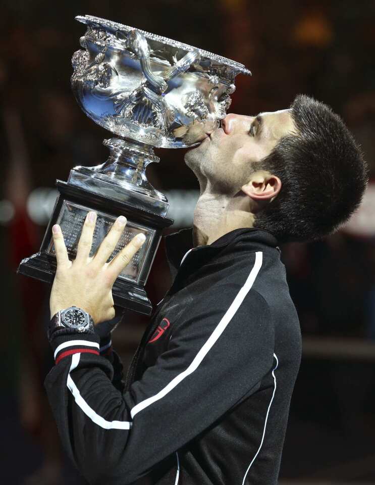 Novak Djokovic gives the winner's trophy a kiss early Monday morning after winning an epic five-set battle over Rafael Nadal in the Australian Open men's final in a record 5 hours 53 minutes.