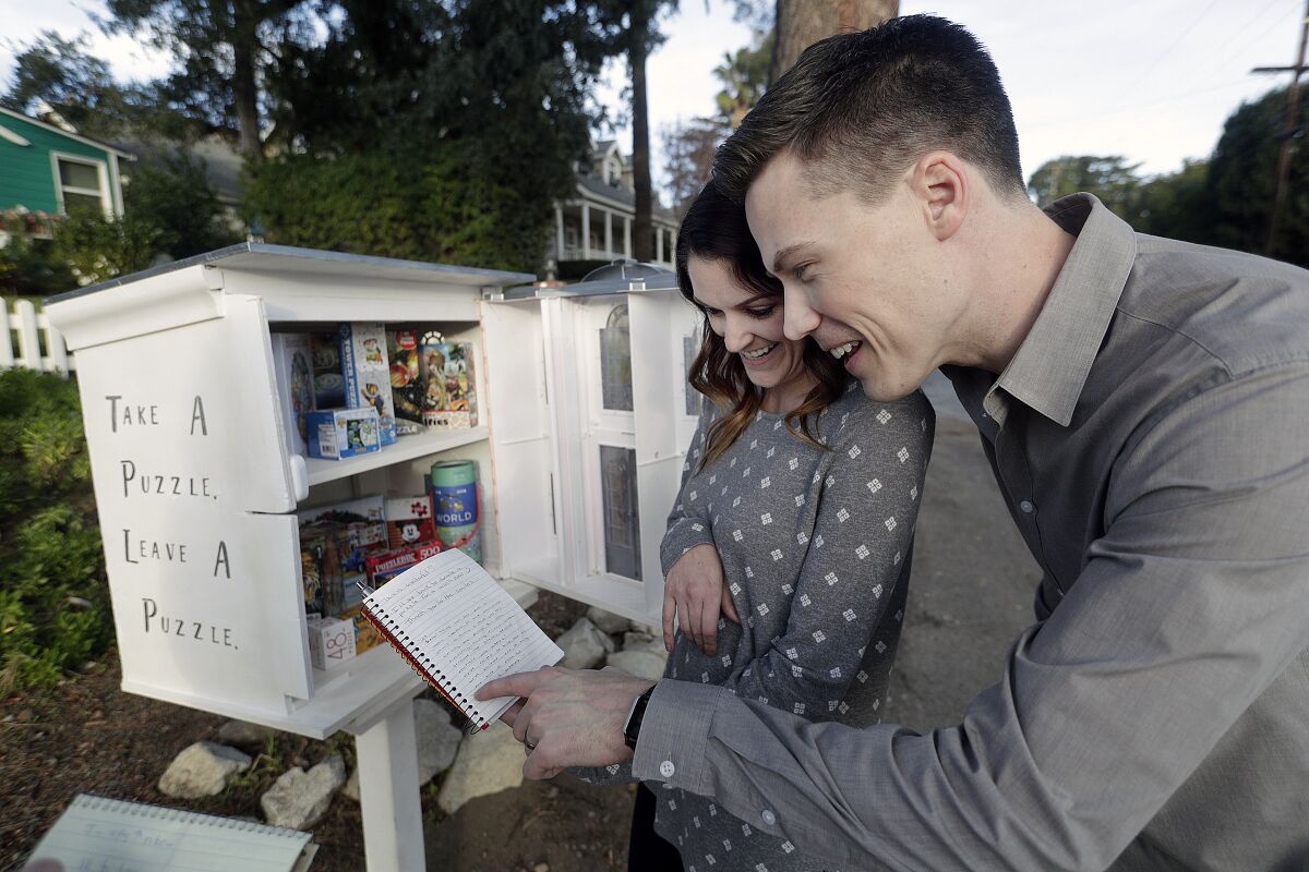 Luke and Jessica Cheney read notes from a comment book they've left inside their new jigsaw puzzle trading post on Mountain Avenue in La Crescenta. So far, The Puzzle Palace is popular with children and adults.