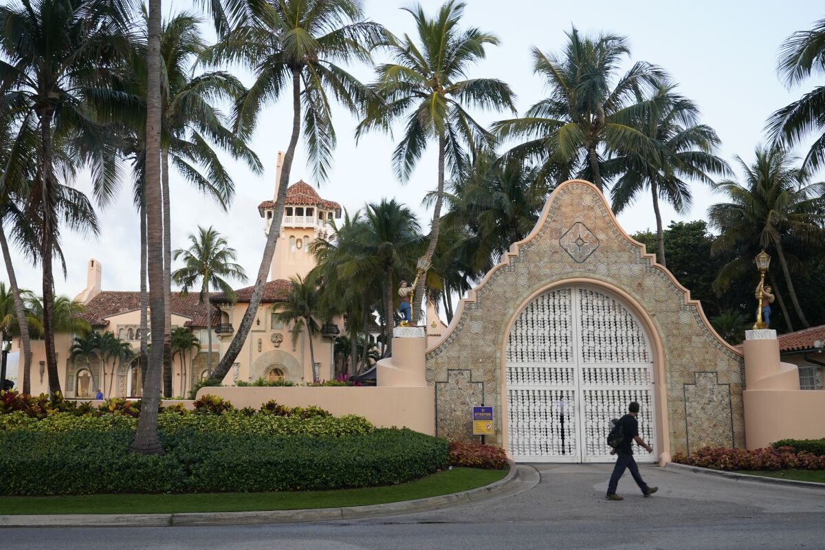 A pedestrian walks by the front gate of the Mar-a-Lago club in Florida.