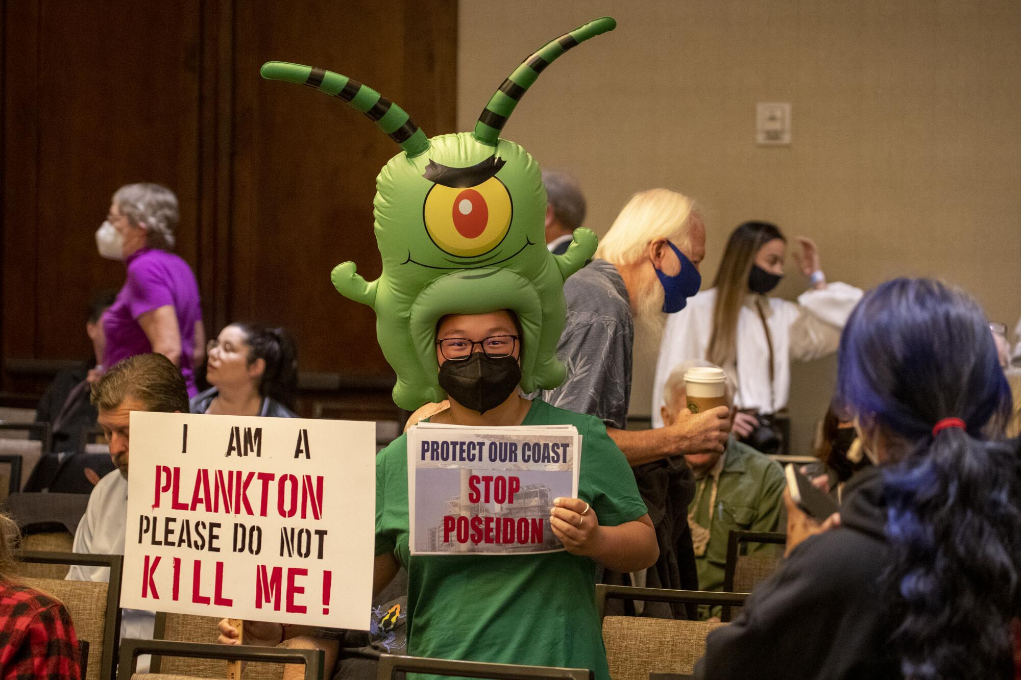 Dressed in a plankton costume, Zoey Lambe-Hommel joins people who gathered before the start of the meeting