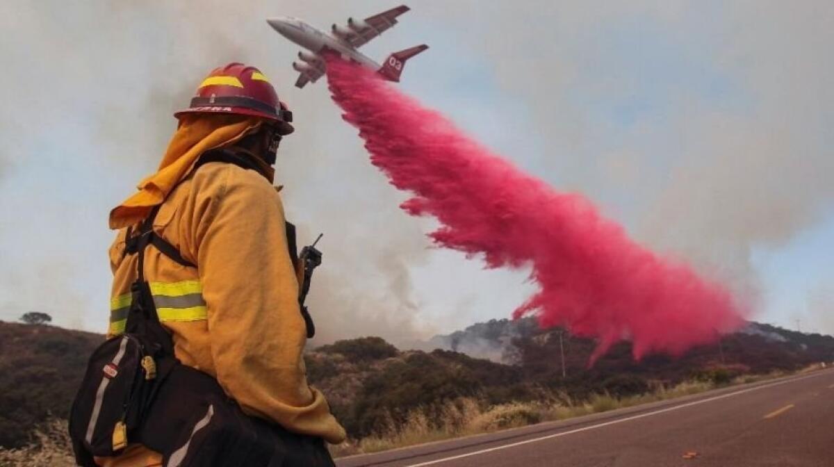 Upland Fire Capt. Joe Burna watches as a tanker drops fire retardant to stop a wildfire from jumping over Highway 94 near Potrero, Calif. in June.