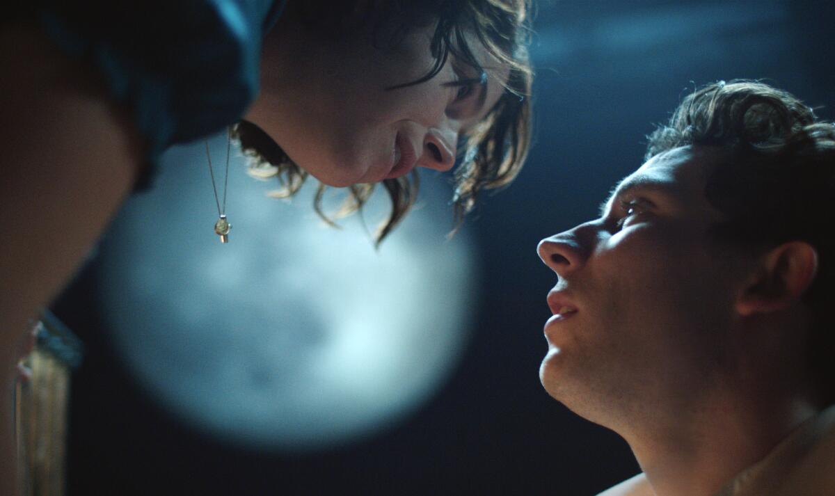 Seen from below, a woman, left, and a man stare at each other