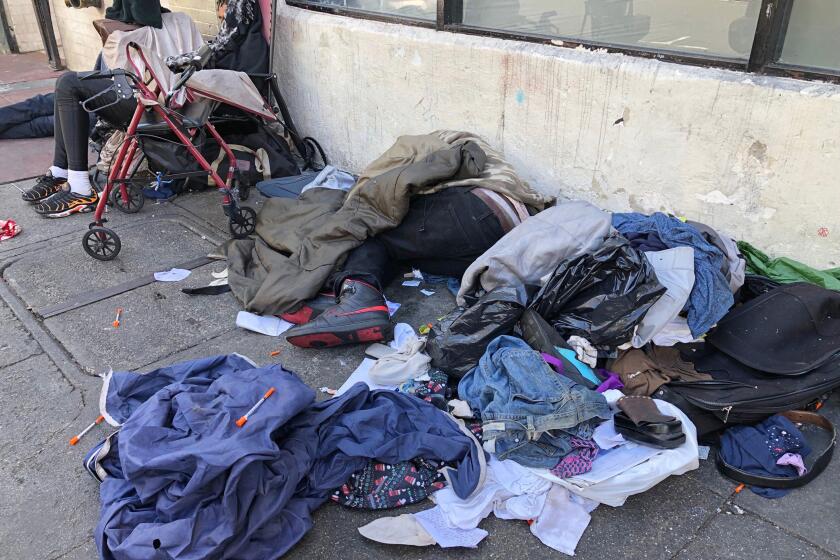 FILE - In this July 25, 2019, file photo, sleeping people, discarded clothes and used needles are seen on a street in the Tenderloin neighborhood in San Francisco. San Francisco is using private donations to deliver alcohol, tobacco and medical marijuana for a few dozen people dealing with addiction as they isolate or quarantine in city-leased hotel rooms during the pandemic, officials confirmed Wednesday, May 6, 2020. (AP Photo/Janie Har, File)