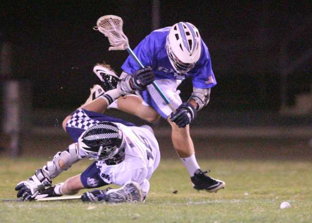 Newport Harbor's Matt Buchanan, bottom, and Corona del Mar's Connor Cruse get tangled up as they fight for the ball during the Battle of the Bay lacrosse match at Newport Harbor High School on Friday.