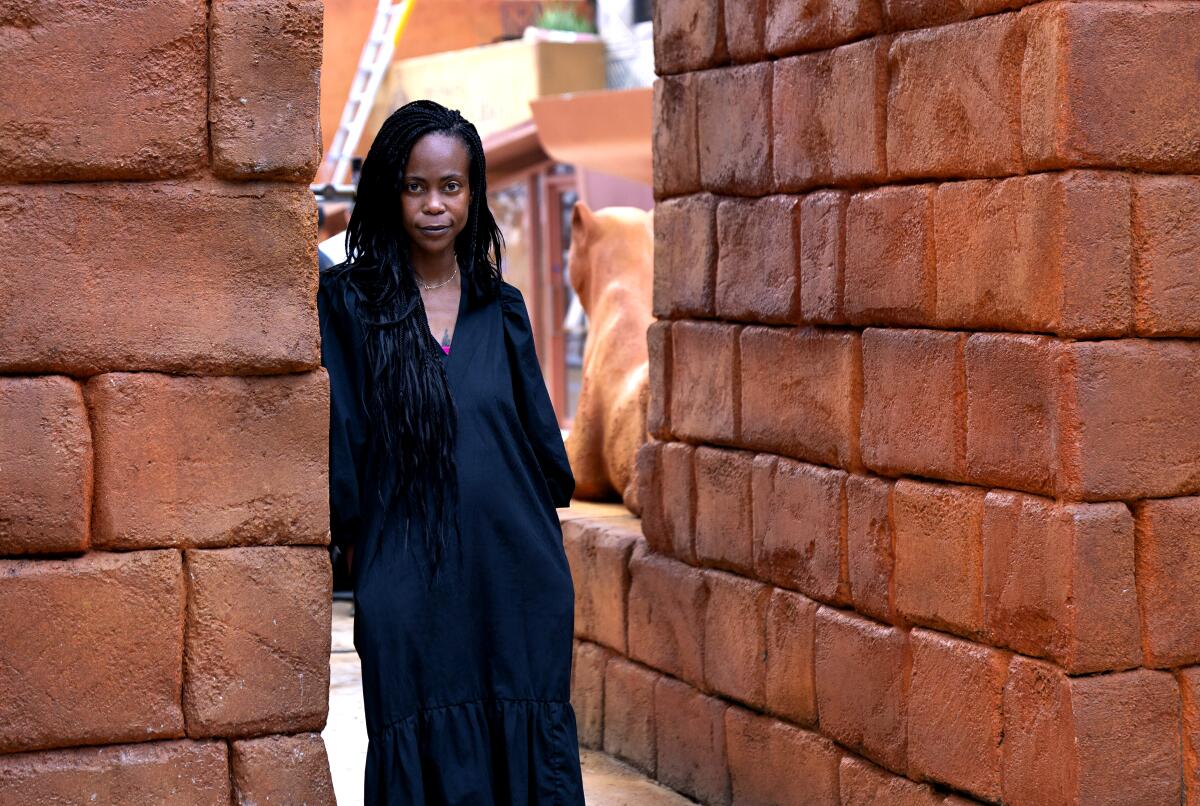Production Designer Hannah Beachler stands against clay brick walls on the set of "Black Panther: Wakanda Forever."