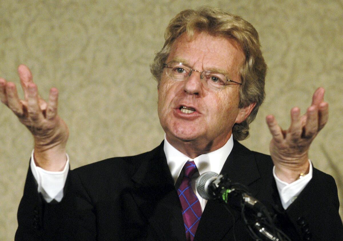 Jerry Springer gestures with both palms facing upward while speaking