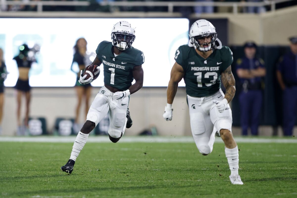 Michigan State's Jayden Reed, left, returns a punt for a touchdown as teammate Ben VanSumeren (13) blocks against Western Kentucky during the first quarter of an NCAA college football game, Saturday, Oct. 2, 2021, in East Lansing, Mich. (AP Photo/Al Goldis)
