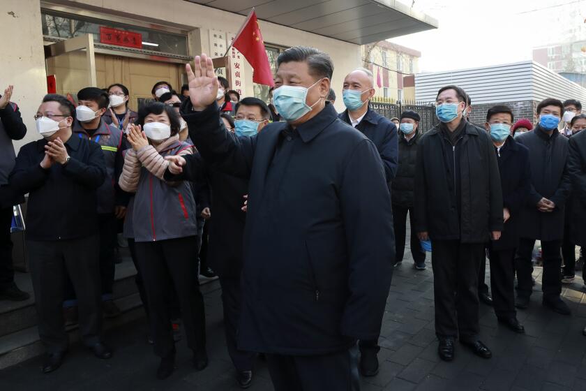 In this photo released by Xinhua News Agency, Chinese President Xi Jinping, centre, wearing a protective face mask waves as he inspects the novel coronavirus pneumonia prevention and control work at a neighbourhoods in Beijing, Monday, Feb. 10, 2020. China reported a rise in new virus cases on Monday, possibly denting optimism that its disease control measures like isolating major cities might be working, while Japan reported dozens of new cases aboard a quarantined cruise ship. (Pang Xinglei/Xinhua via AP)