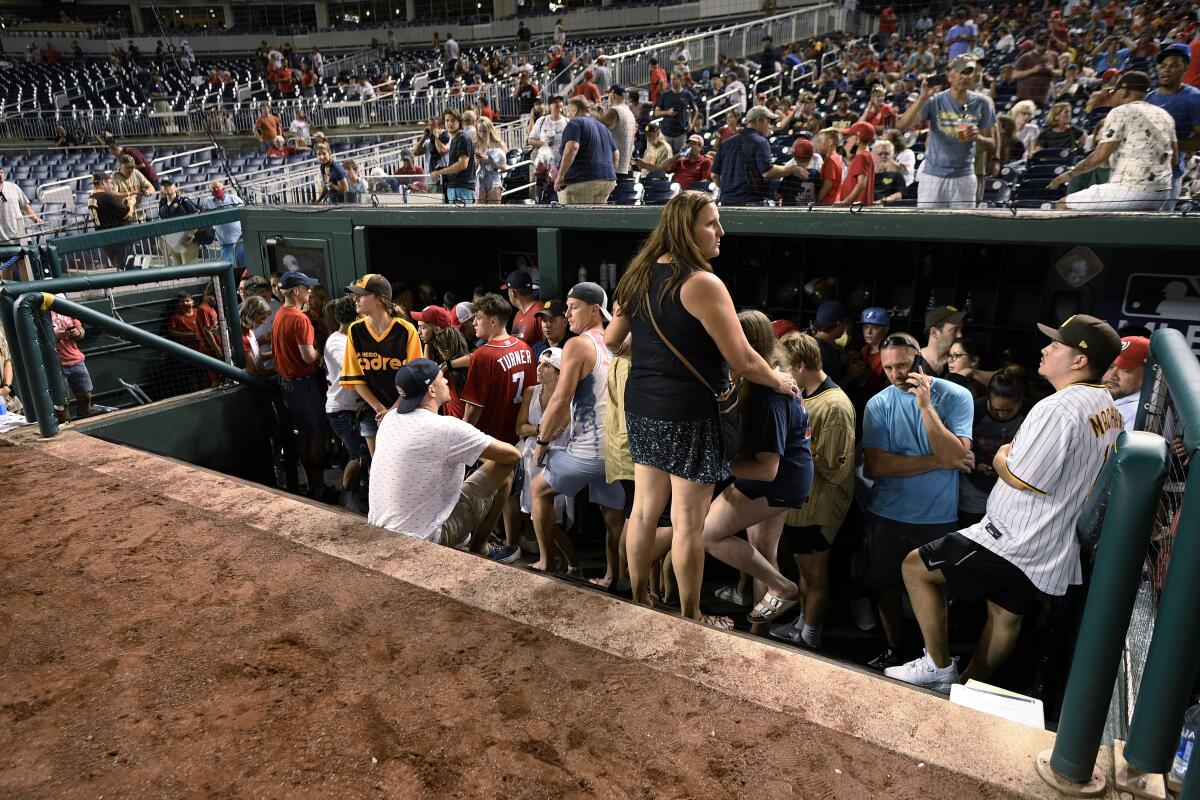 Spectators stand in the visiting team dugout during a stoppage in play in the sixth inning July 17, 2021.