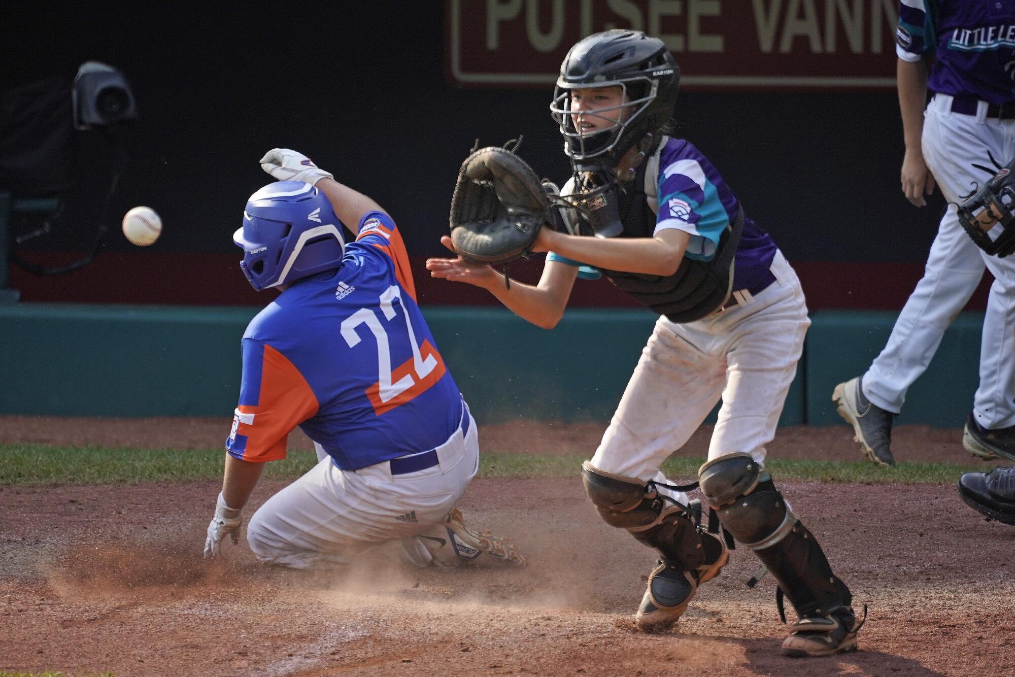 Taylor, Mich.'s Jackson Surma scores on a sacrifice fly as Abilene, Texas catcher Ella Bruning receives a late relay throw .