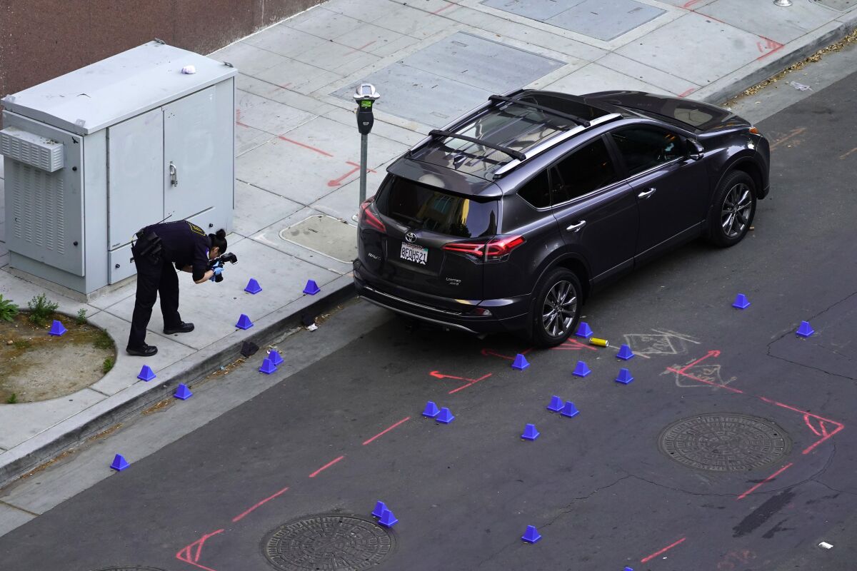 A crime scene investigator photographs evidence markers in Sacramento, Calif. April 3, 2022.