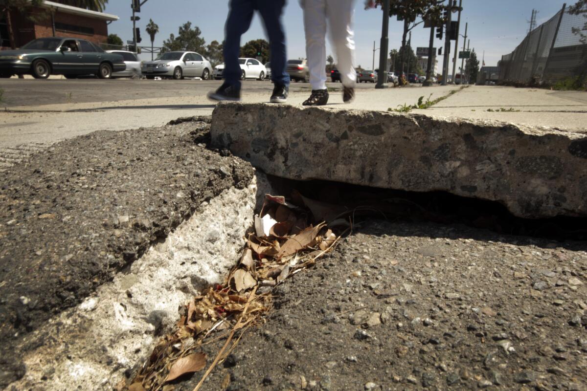 Two people navigate the sidewalk along Vermont Avenue where it meets the 101 Freeway.