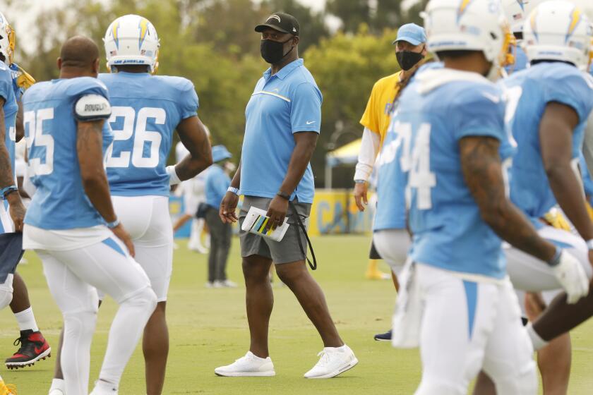 COSTA MESA, CA - AUGUST 17: Head Coach Anthony Lynn, center, works with players of the Los Angeles Chargers football team.