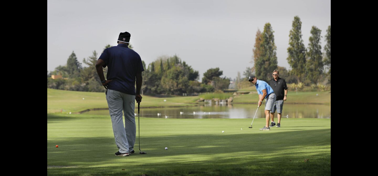Napoleon McCallum who played football for the U.S.Naval Academy and Oakland Raiders, left, looks on, as Rick Doubleday putts on the 2nd green as Ken Sayer, right, looks on. They were playing in the Navy-Notre Dame Golf Tournament at the Riverwalk Golf Club in Mission Valley in advance of the football game between the two schools to be held at SDCCU Stadium, Saturday.
