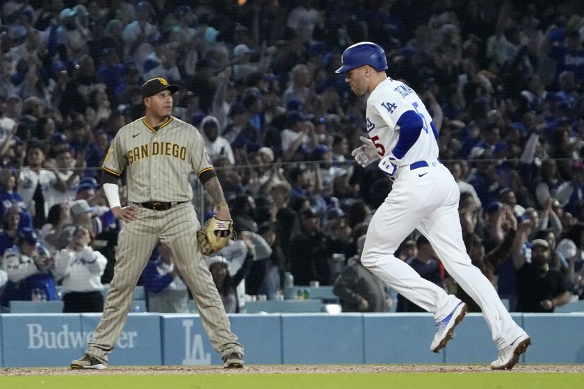 Los Angeles Dodgers' Freddie Freeman, right, gestures as he heads to third after hitting a solo home run as San Diego Padres third baseman Manny Machado stands by during the seventh inning of a baseball game Friday, May 12, 2023, in Los Angeles. (AP Photo/Mark J. Terrill)