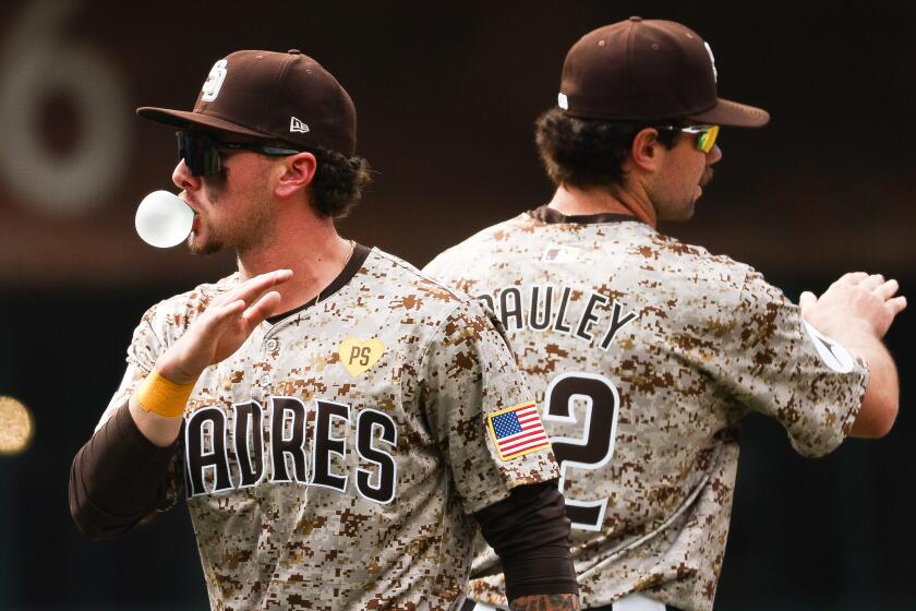 San Diego, CA - March 31: San Diego Padres center fielder Jackson Merrill (3) blows a bubble as he high fives third baseman Graham Pauley (22) after the Padres beat the San Francisco Giants at Petco Park on Sunday, March 31, 2024 in San Diego, CA. (Meg McLaughlin / The San Diego Union-Tribune)