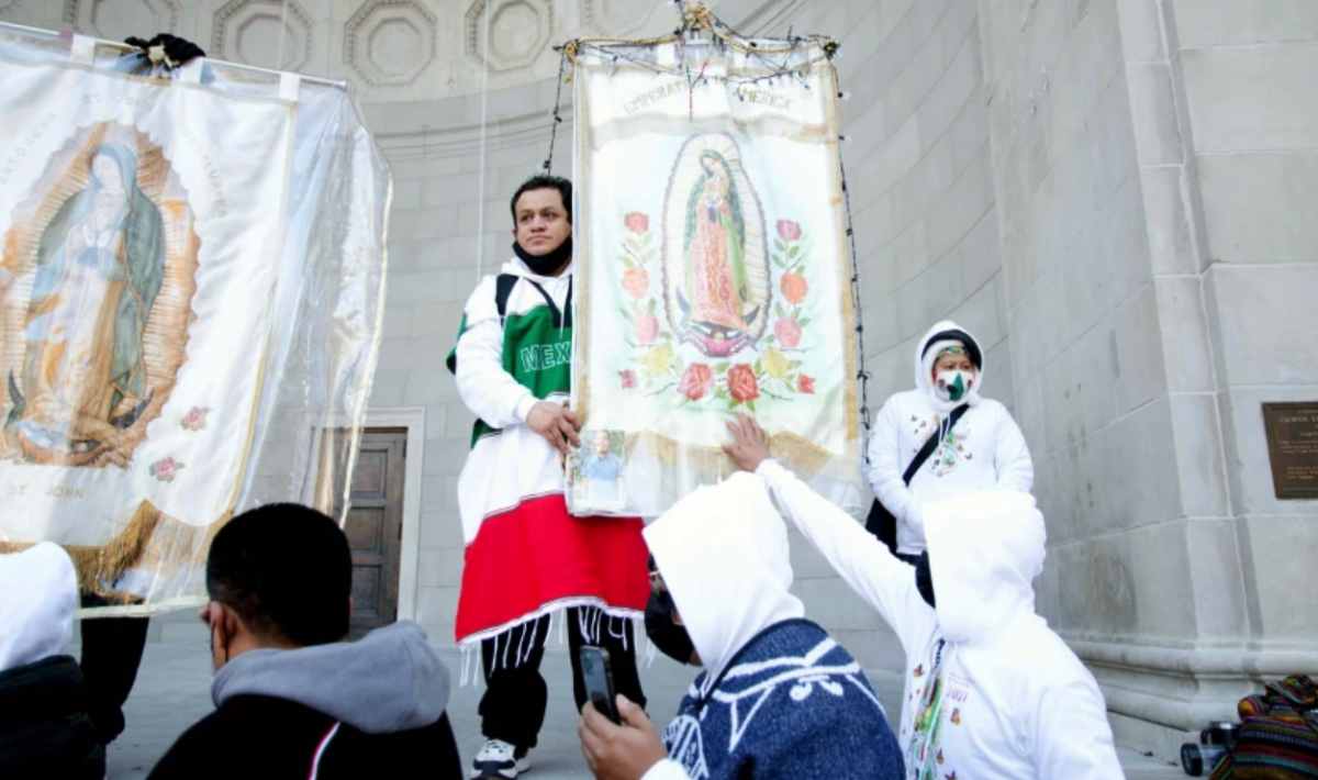 Un grupo de personas pasa delante de las imágenes de la virgen de Guadalupe