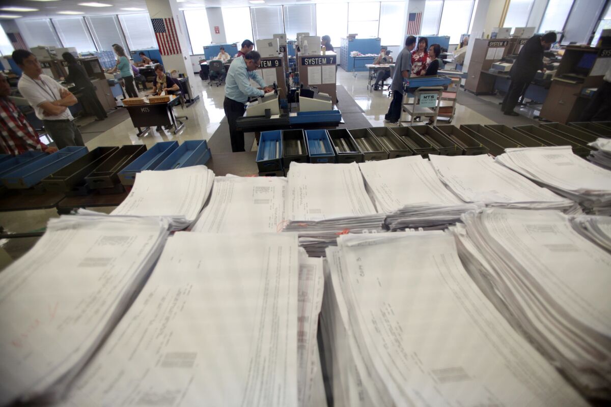 County workers load ballots into computers at the registrar recorder's office in Norwalk after the November 2012 election. Election officials said that adding school district elections to the already-crowded November ballot would exceed their ability to conduct elections.