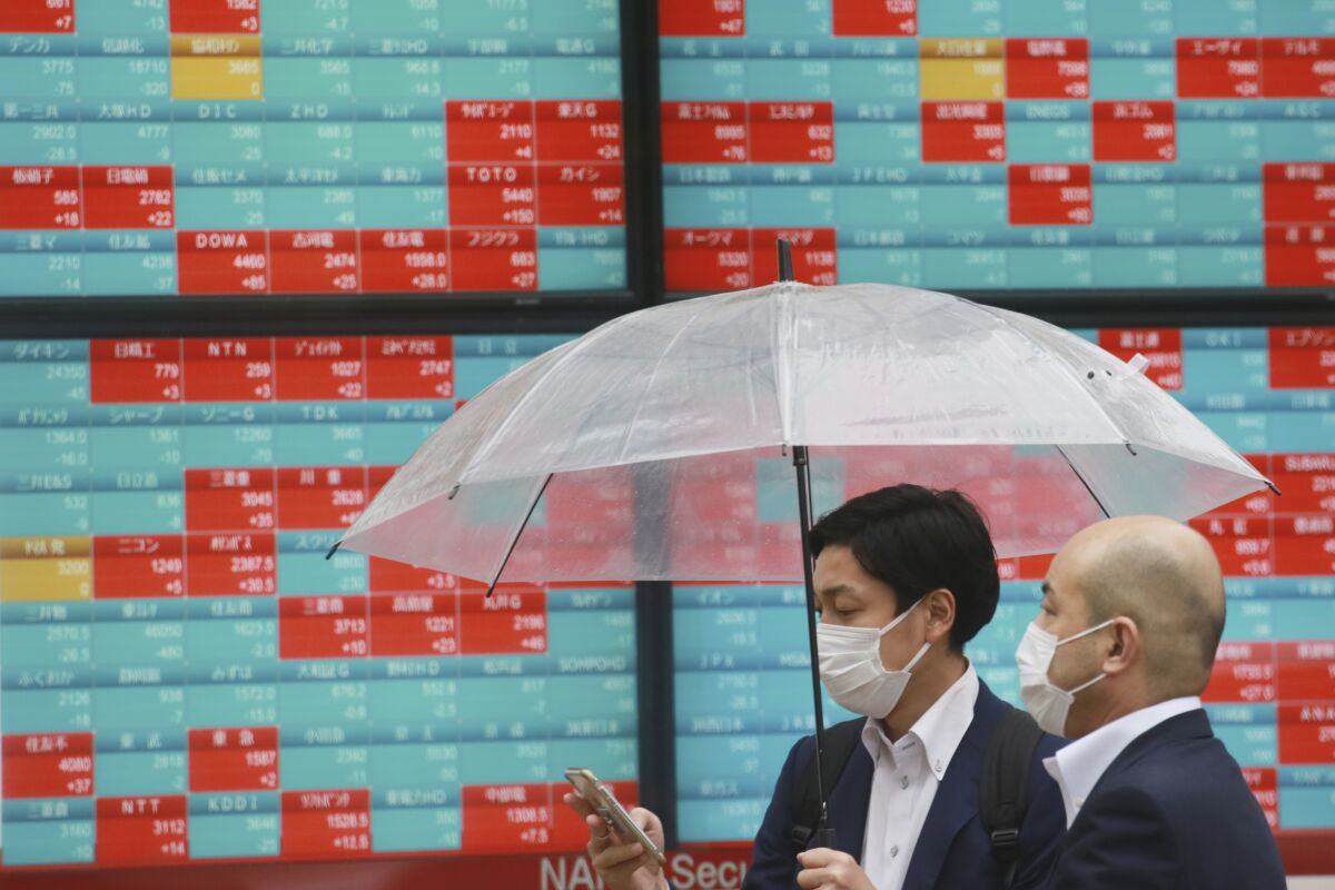 People walk by an electronic stock board of a securities firm in Tokyo, Wednesday, Oct. 13, 2021. Shares were mixed in Asia on Wednesday after an up-and-down day on Wall Street ended with most benchmarks lower as traders waited for updates on inflation and corporate earnings. (AP Photo/Koji Sasahara)