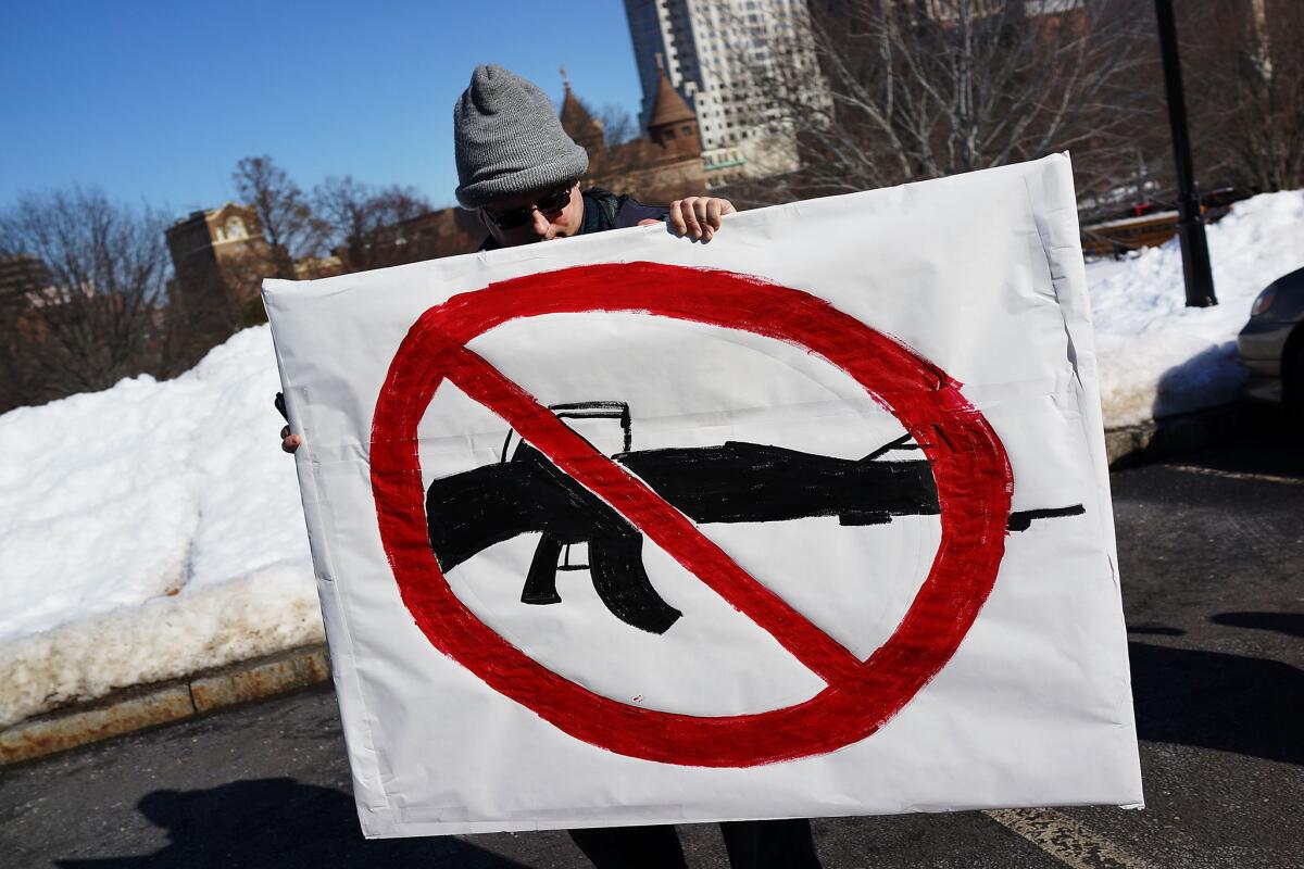 A man holds up a sign with a depiction of an assault weapon during a rally at the Connecticut State Capital to promote gun control legislation in the wake of the Dec. 14 school shooting in Newtown.