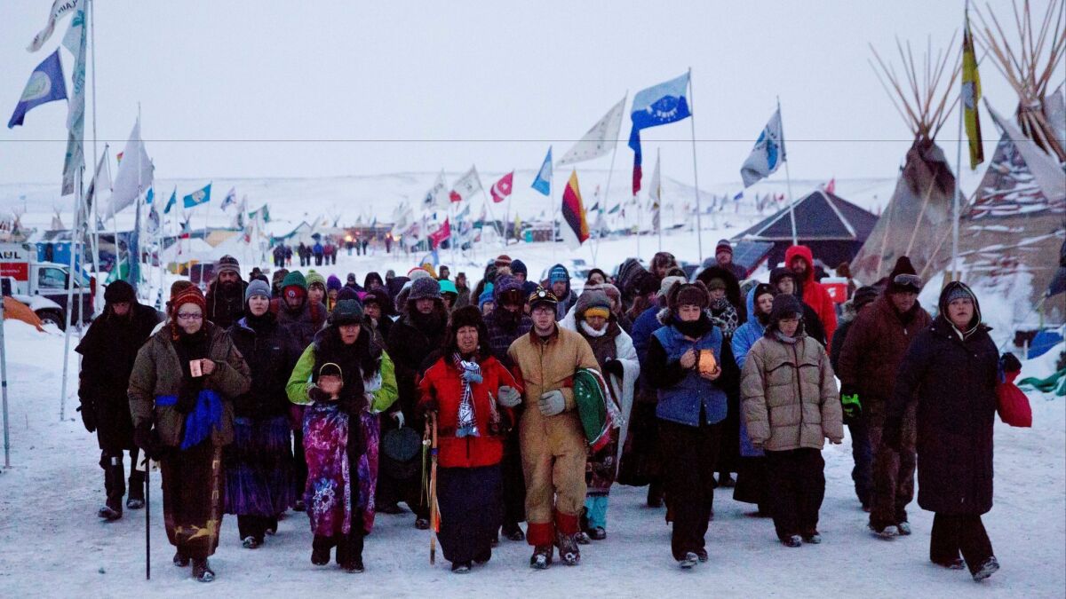 Beatrice Menase Kwe Jackson, center, and Daniel Emory, both of the Ojibwe Tribe, lead a procession to the Cannonball River in December as part of protests against the Dakota Access oil pipeline in Cannon Ball, N.D.