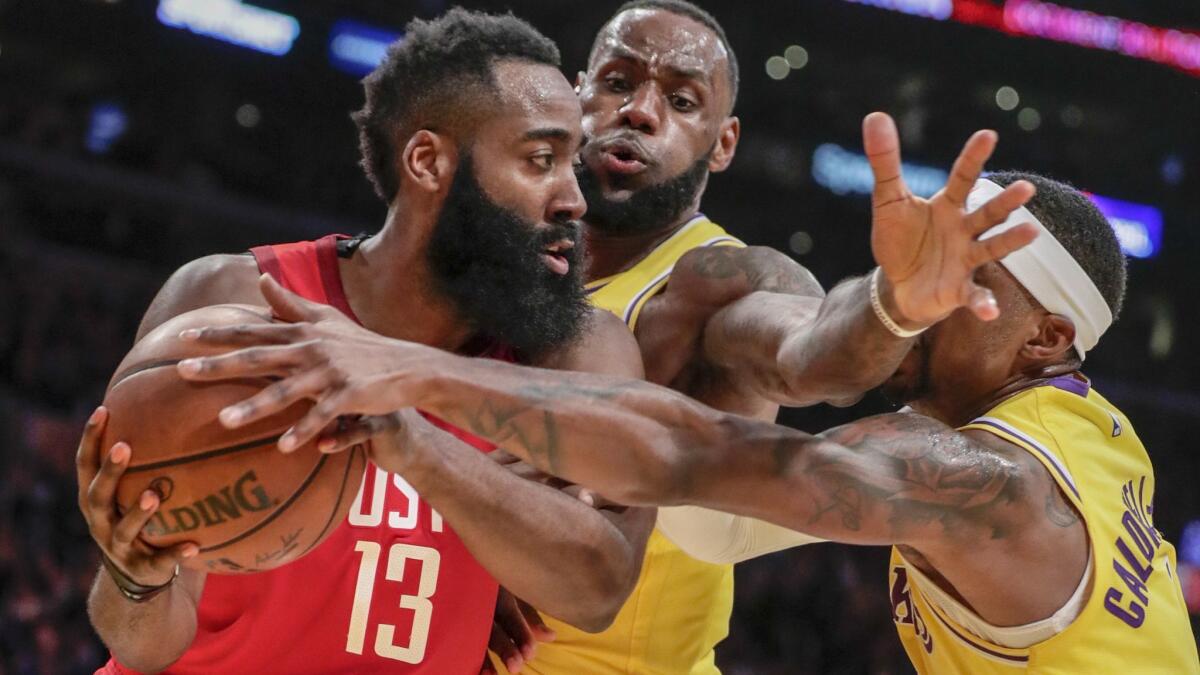 Houston Rockets guard James Harden is defended tightly by Lakers forward LeBron James and guard Kentavious Caldwell-Pope during second half on Thursday at Staples Center.