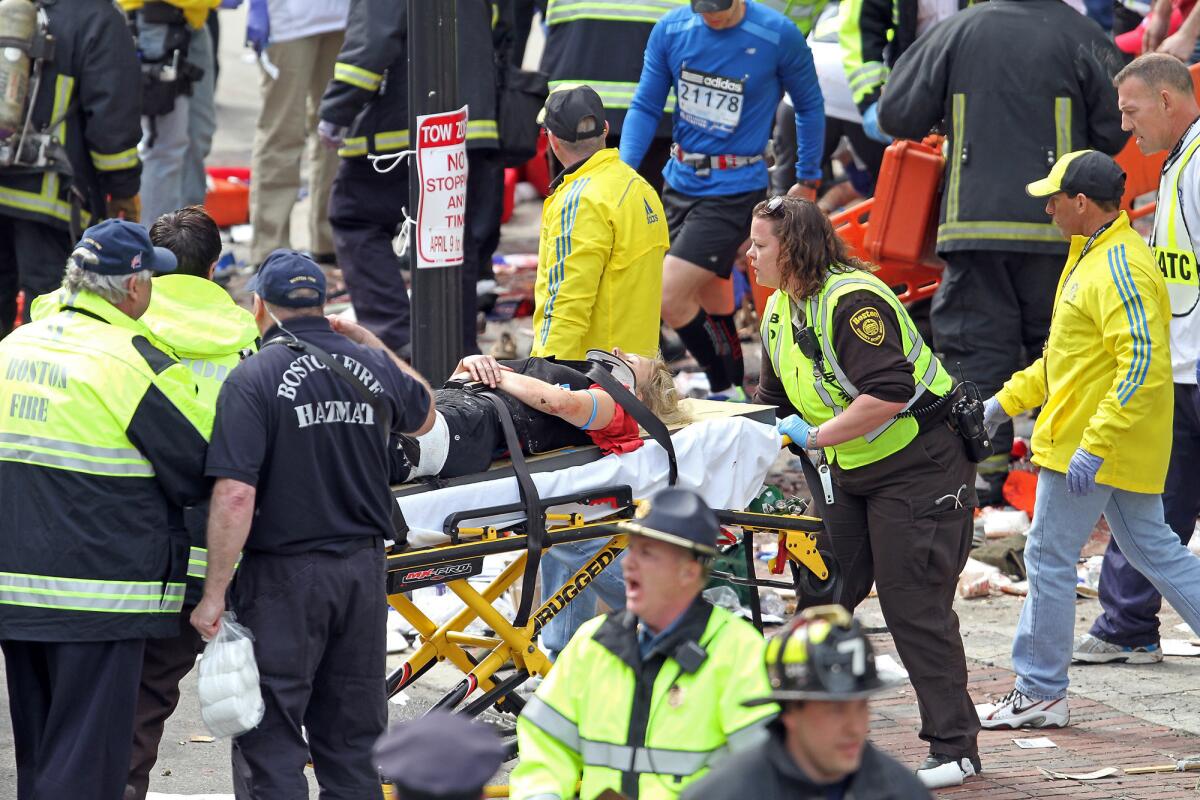 Rescue personnel aid injured people near the finish line of the 2013 Boston Marathon following explosions.