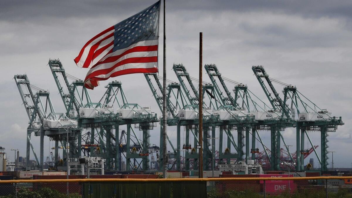 Flags fly over shipping cranes and containers in Long Beach, Calif. The skyrocketing U.S. trade deficit last year hit the highest level in a decade, a major setback for President Trump's global trade offensive.