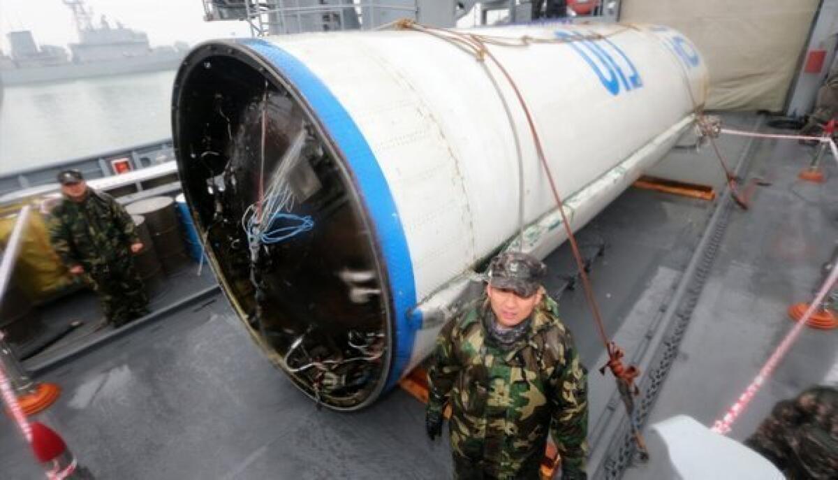 South Korean sailors in Pyeongtaek, South Korea, stand guard near recovered debris believed to be a fuel container of the first-stage rocket from North Korea's recent launch.