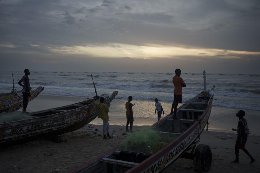 FILE - Senegalese youth gather around pirogues on the beach at dusk in Fass Boye, Senegal, Aug. 29, 2023. (AP Photo/Felipe Dana, File)