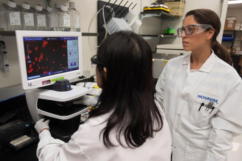 Dr. Sonia Macieiewski (R) and Dr. Nita Patel, look at a sample of a respiratory virus at Novavax labs.