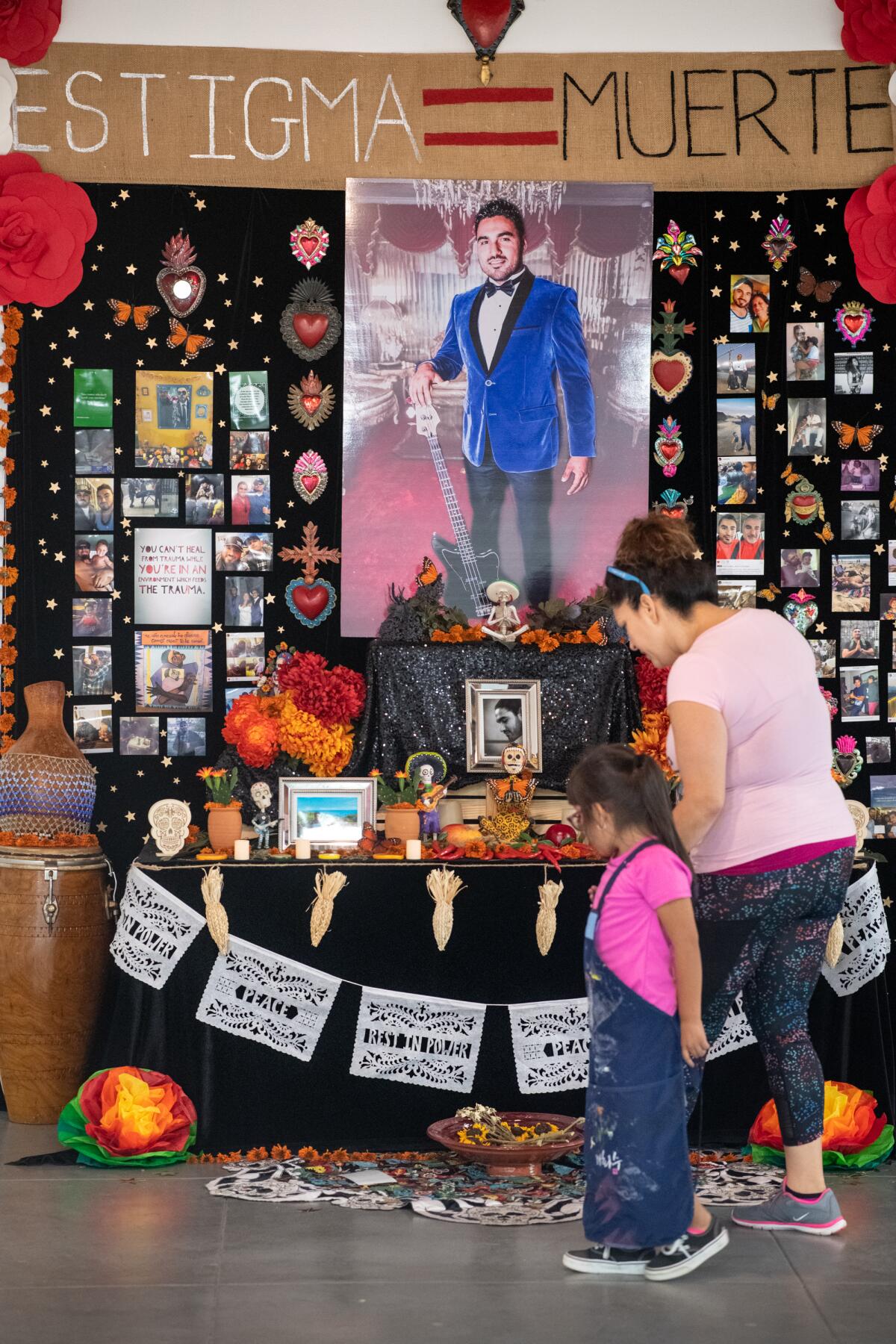 Lorena Lopez and Maria Bustamante Morales, 4, look at the Day of the Dead "Altar for Carlos Zaragoza" at Self Help Graphics & Art.
