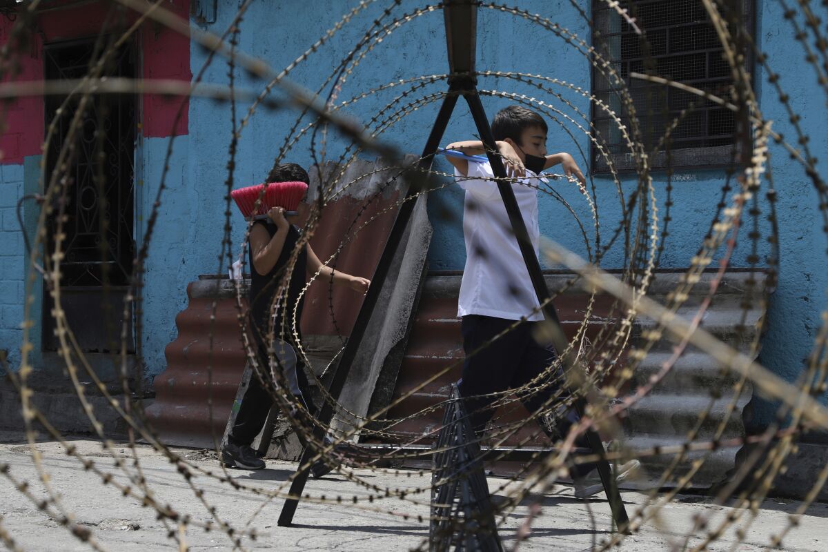 Children walk behind concertina wire